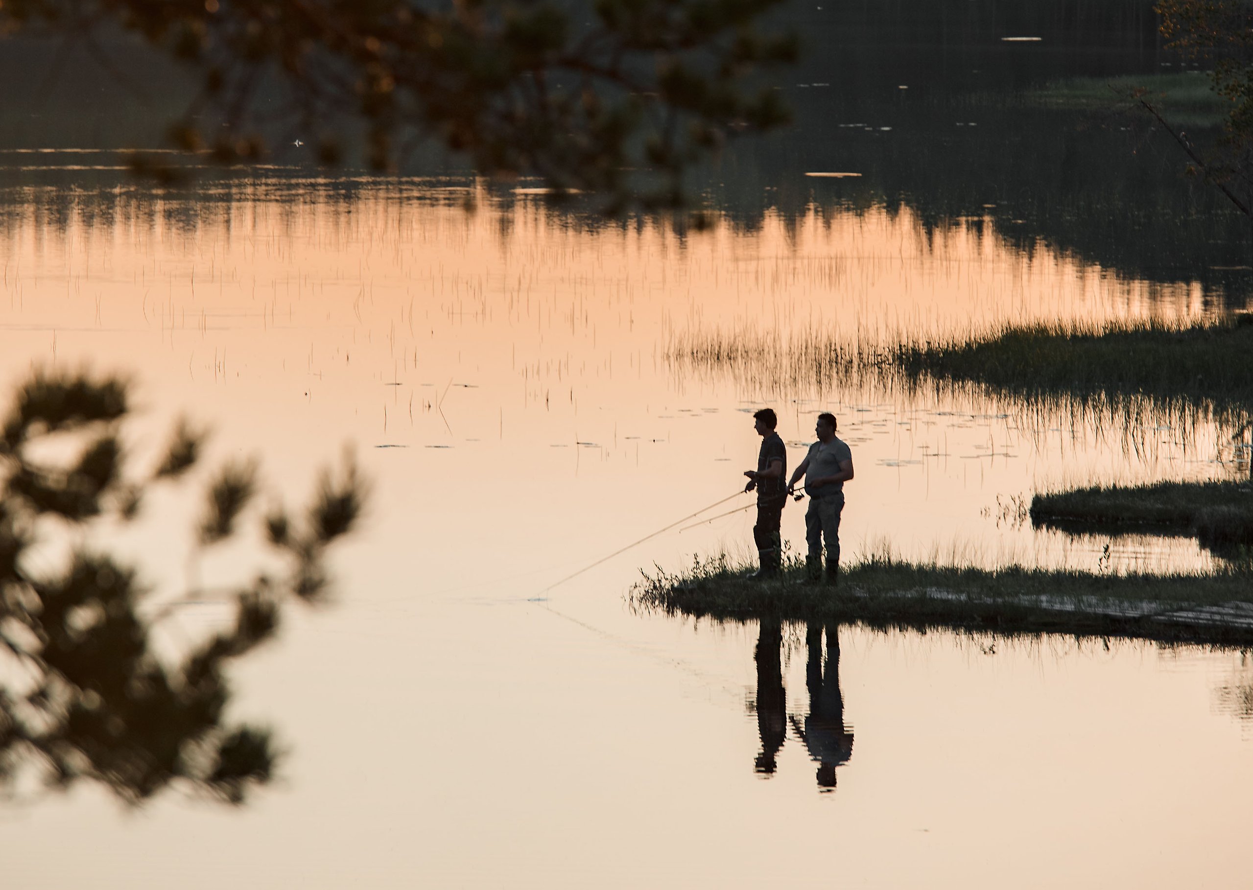 Bild på en sjö med en flytbrygga som två barn badar ifrån