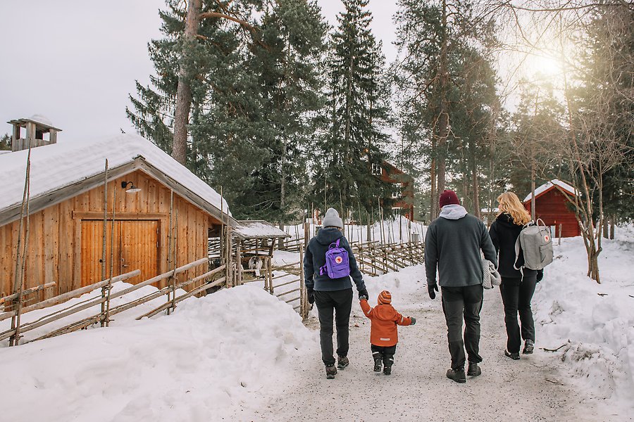 En familj på fyra personer går omkring på Norra Berget i Sundsvall. De går på en gångväg, det är snö överallt och framför familjen finns flera djurhägn med får och getter.