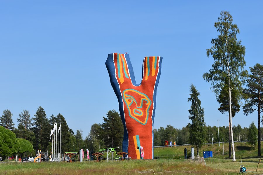 En stor skulptur format som ett Y. Den är röd och blå och står i naturen. foto.  